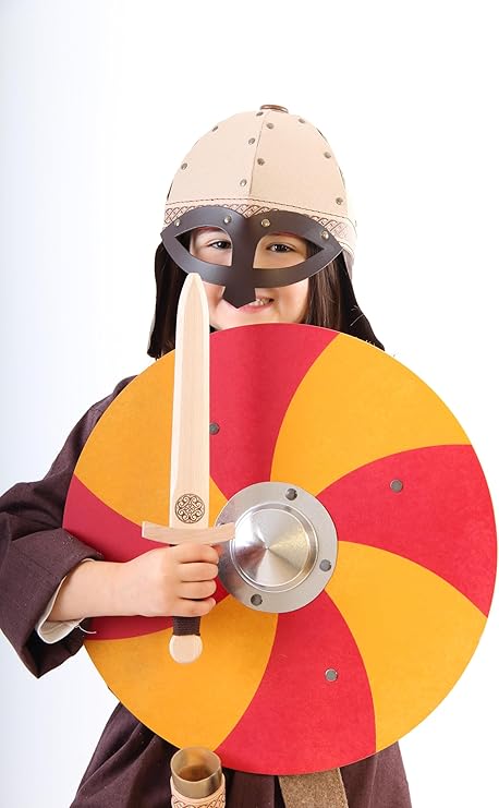 Kind in Wikingerverkleidung mit hellem Helm und Gesichtsmaske hält ein rundes Holzschild mit rot-gelbem Spiralmuster und ein Holzschwert; im Hintergrund ein heller, neutraler Hintergrund.