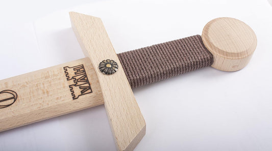 Nahaufnahme eines Holzschwertes mit rundem Knauf, braun umwickeltem Griff und Querstück, das mit einer Zierniete und dem eingebrannten VAH-Logo versehen ist.
