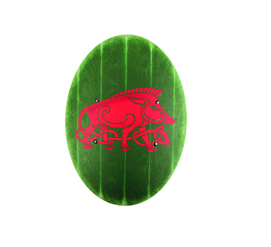Ovaler grüner Schild mit sichtbarer Holzstruktur und stilisiertem roten Wildschweinmotiv in keltischem Design, vor weißem Hintergrund.