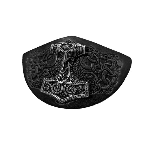 „Ein Lederstück mit einem silbernen Anhänger in Form eines Wikingerhammer, umgeben von kunstvollen keltischen Verzierungen.“