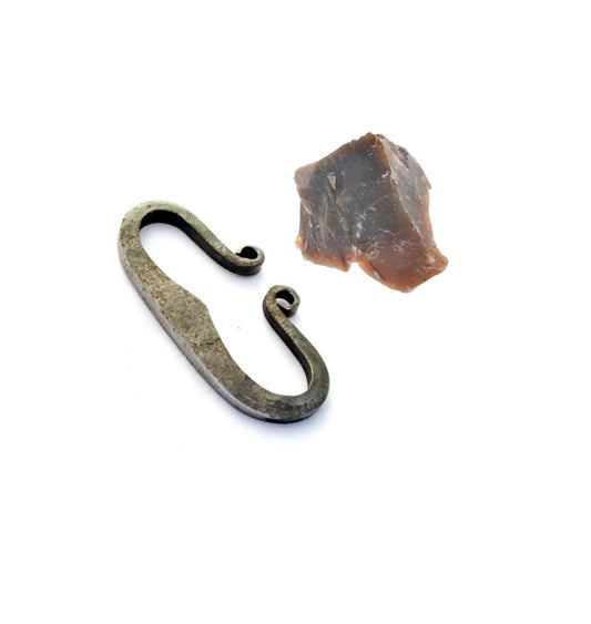 Traditioneller Feuerstahl mit geschmiedetem Haken-Design, zusammen mit einem Stück Feuerstein auf weißem Hintergrund.